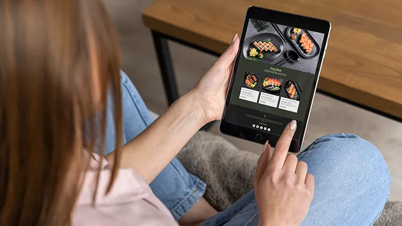 Experiencia de usuario UX UI en gastronomía - Cliente usando menú digital en tablet para hacer pedido en restaurante.