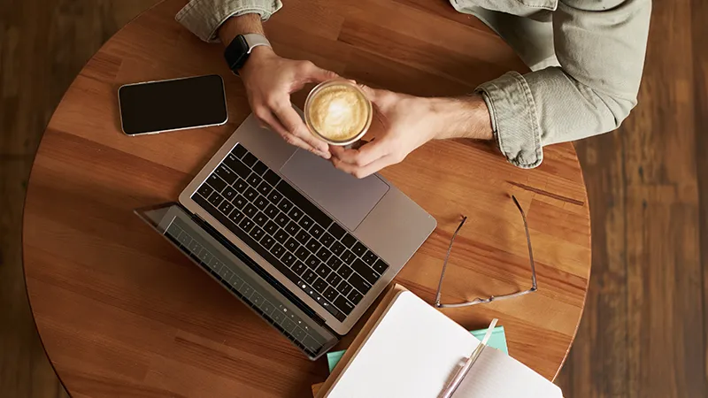 Persona trabajando con portátil y café, representando gestión de dominios y hosting para hostelería