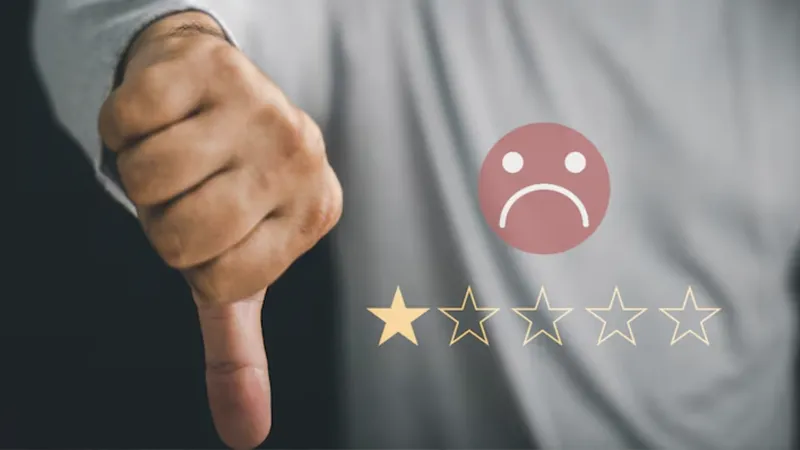 Mano haciendo el gesto de pulgar hacia abajo junto a una sola estrella dorada y un icono de cara triste representando una reseña negativa.
