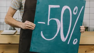 Camarero con delantal sosteniendo un cartel de pizarra con un descuento del 50% escrito a tiza